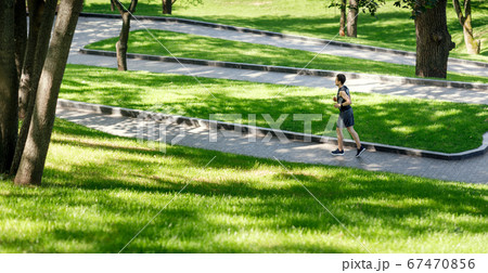 Jogging in modern park. Guy in sportswear runs at winding path Jogging in modern park. Guy in sportswear runs at winding path 67470856