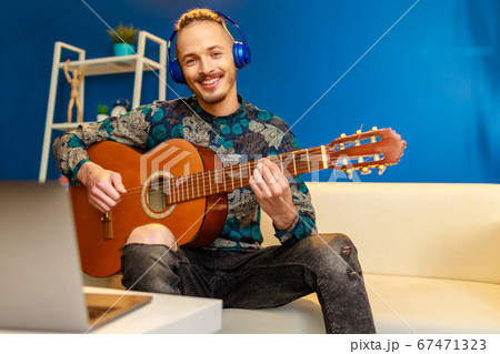 Young stylish caucasian man taking guitar class online at home using his laptop 67471323