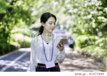 新緑の木々の中スマホを使用している若い女性 新緑の木々の中スマホを使用している若い女性 67471993