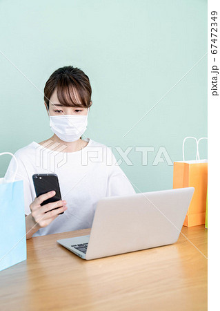 スマホとパソコンでオンラインショッピングをする若い女性 【マスク着用】 スマホとパソコンでオンラインショッピングをする若い女性 【マスク着用】 67472349