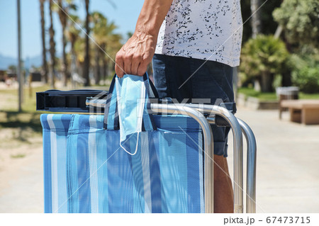 man carrying a surgical mask and a deck chair man carrying a surgical mask and a deck chair 67473715