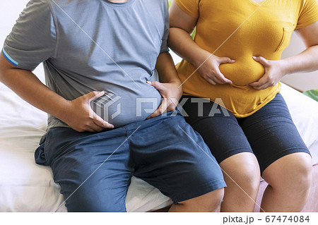Fat man and woman holding their big belly while Fat man and woman holding their big belly while 67474084