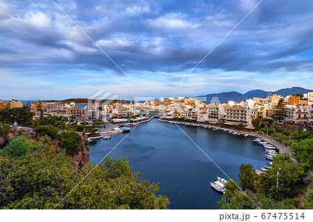 Colorful view of Voulismeni lake and Agios Nikolaos town on Crete island, Greece in evening with beautiful clouds on blue sky. 67475514