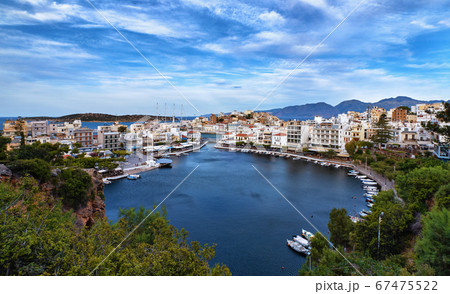 Colorful view of Voulismeni lake and Agios Nikolaos town on Crete island, Greece in evening with beautiful clouds on blue sky. 67475522