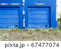 overgrown entry into the gates of an abandoned car service. it is written on the facade - quick service and service 67477074