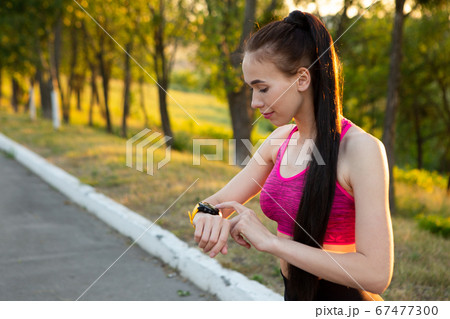 Sportwoman checking fitness and health tracking wearable device Sportwoman checking fitness and health tracking wearable device 67477300