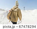 a man with a backpack walks along the white sand towards an abandoned old iron tower 67478294