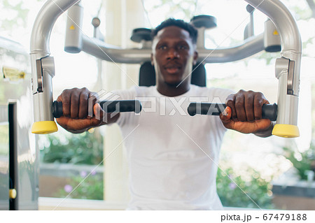 African American athlete doing exercise for chest muscles on pec deck machine during workout in gym 67479188