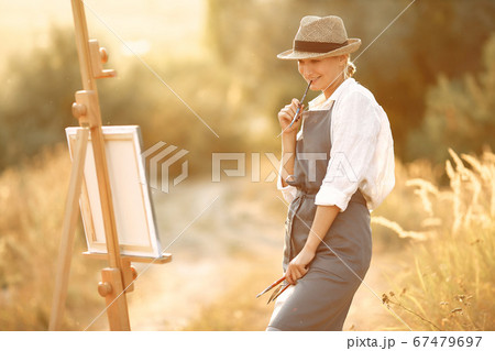 Woman in a apron painting in a field 67479697