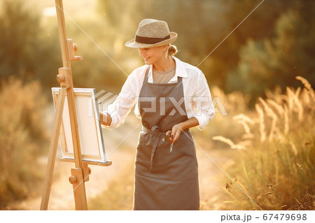 Woman in a apron painting in a field 67479698