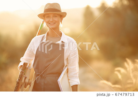 Woman in a apron painting in a field 67479713