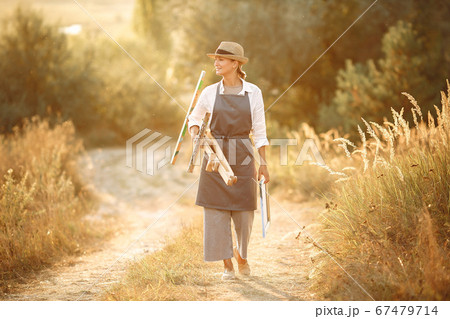 Woman in a apron painting in a field Woman in a apron painting in a field 67479714