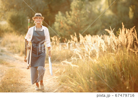 Woman in a apron painting in a field Woman in a apron painting in a field 67479716