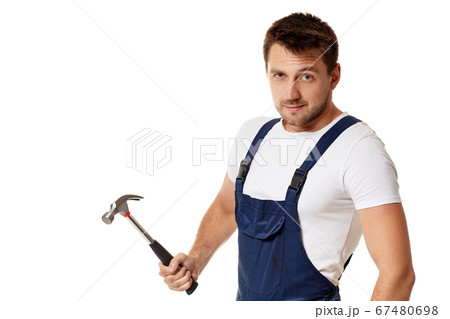 Angry construction worker raises hammer and looks at camera 67480698