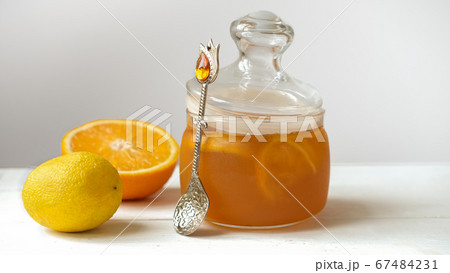 orange and lemon jelly or jam in a glass jar with spoon 67484231