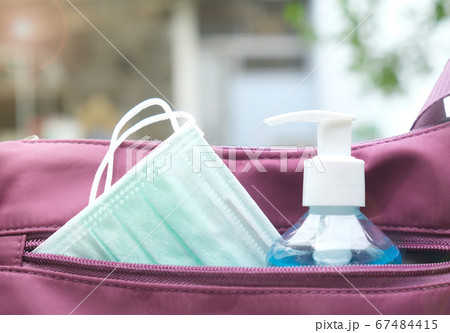 Surgical mask and alcohol gel bottle in handbag. Surgical mask and alcohol gel bottle in handbag. 67484415