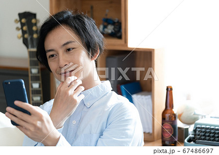 スマホでテレビ電話をする男性【リビング】 スマホでテレビ電話をする男性【リビング】 67486697