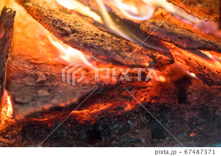 Flame incinerates firewood and transforms it ashes, close up, shallow depth of field. Blaze in a large stove. Nature texture of fire. The flame of fire burns in the brazier, smoldering firewoods. 67487371