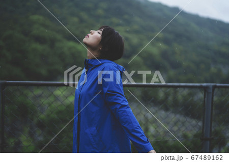 雨の中でレインコートを着た女性の写真素材