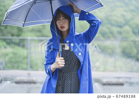 雨の中でレインコートを着た女性の写真素材