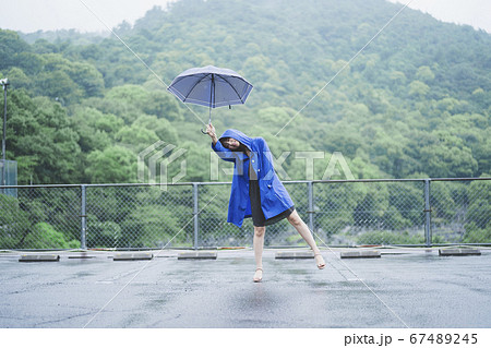 雨の中でレインコートを着た女性の写真素材