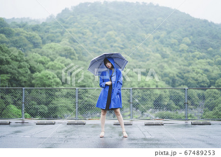 雨の中でレインコートを着た女性の写真素材