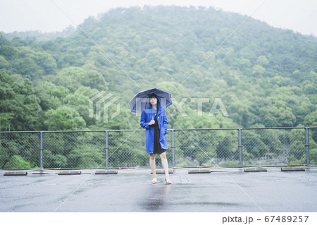 雨の中でレインコートを着た女性の写真素材