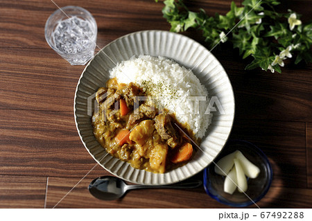 野菜がたくさん入った牛すじカレーとトッピングのらっきょうとお冷を俯瞰で撮影 67492288