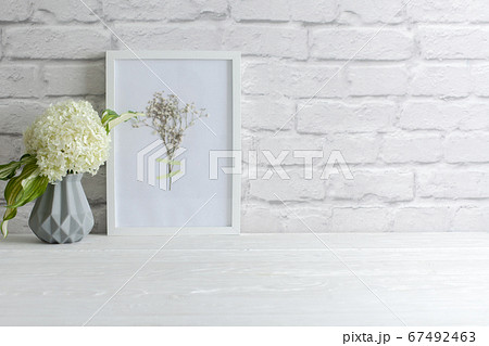 Green hydrangea in a gray vase in the Nordic style stands on a white wooden table. Background old brick. Bundle, copy space. Green hydrangea in a gray vase in the Nordic style stands on a white wooden table. Background old brick. Bundle, copy space. 67492463