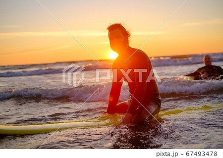Surfer sitting on surfboard in sea 67493478