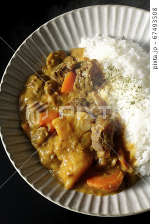 熱々で湯気が上がるジャガイモ、人参、牛すじ肉がたくさん入ったカレーライス（黒背景） 67493508