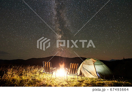 Tourist camping at night in the mountains under starry sky 67493664