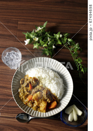 野菜がたくさん入った熱々牛すじカレーとトッピングのらっきょうとお冷を俯瞰で撮影 野菜がたくさん入った熱々牛すじカレーとトッピングのらっきょうとお冷を俯瞰で撮影 67494698