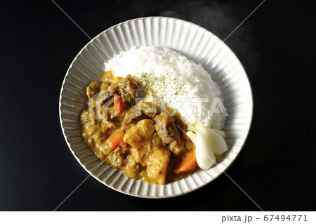黒背景で撮影した人参やジャガイモ、牛すじ肉がたっぷり入った熱々のカレーライス（俯瞰） 67494771
