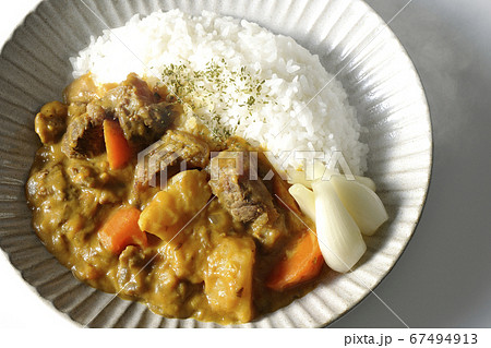 らっきょうがトッピングされているジャガイモや人参がたくさん入った熱々牛すじカレー（白背景、俯瞰） 67494913