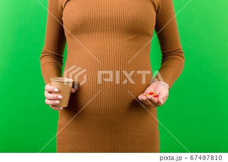 Close up of a paper cup and a heap of pills in 67497810