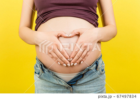Close up of pregnant woman in unzipped jeans 67497834