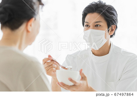 マスクをつけて食事介助を行う介護スタッフ マスクをつけて食事介助を行う介護スタッフ 67497864
