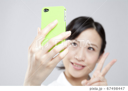携帯電話で自撮りする女性 携帯電話で自撮りする女性 67498447
