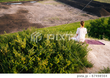 Rear view of woman enjoying meditation on top of rock background of beautiful landscape. Rear view of woman enjoying meditation on top of rock background of beautiful landscape. 67498564