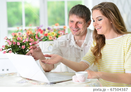 Young couple sitting at table and using laptop Young couple sitting at table and using laptop 67504387