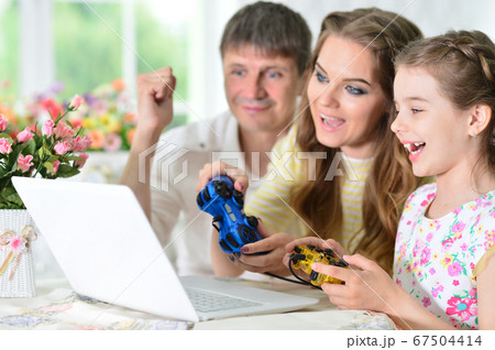 Young family sitting at table and playing video game 67504414