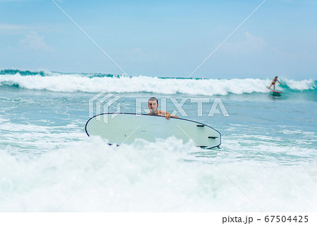 The guy is swimming on the surf board on the 67504425