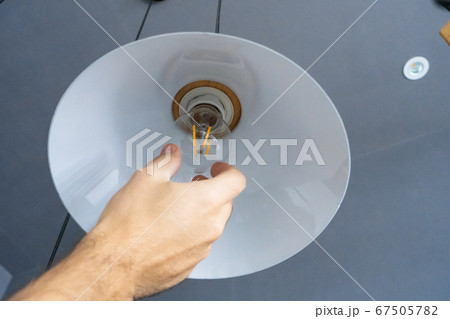 Close-up. A hand changes a light bulb in a stylish Close-up. A hand changes a light bulb in a stylish 67505782