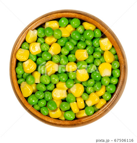 Green peas and corn in wooden bowl. Mixed vegetables. Seeds of pod fruit Pisum sativum and blanched yellow vegetable maize, Zea mays, also called sugar or pole corn. Closeup, from above, food photo. 67506116