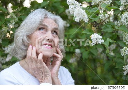 Senior beautiful woman with lilacs in park 67506505