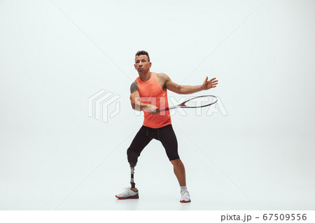 Athlete with disabilities or amputee isolated on white studio background. Professional male tennis player with leg prosthesis training and practicing in studio. 67509556