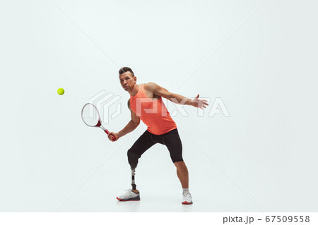 Athlete with disabilities or amputee isolated on white studio background. Professional male tennis player with leg prosthesis training and practicing in studio. Athlete with disabilities or amputee isolated on white studio background. Professional male tennis player with leg prosthesis training and practicing in studio. 67509558