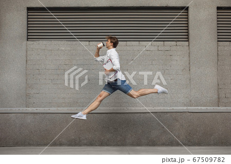 Jumping young man in front of buildings, on the run in jump high Jumping young man in front of buildings, on the run in jump high 67509782