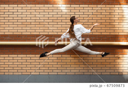 Jumping young woman in front of buildings, on the run in jump high Jumping young woman in front of buildings, on the run in jump high 67509873